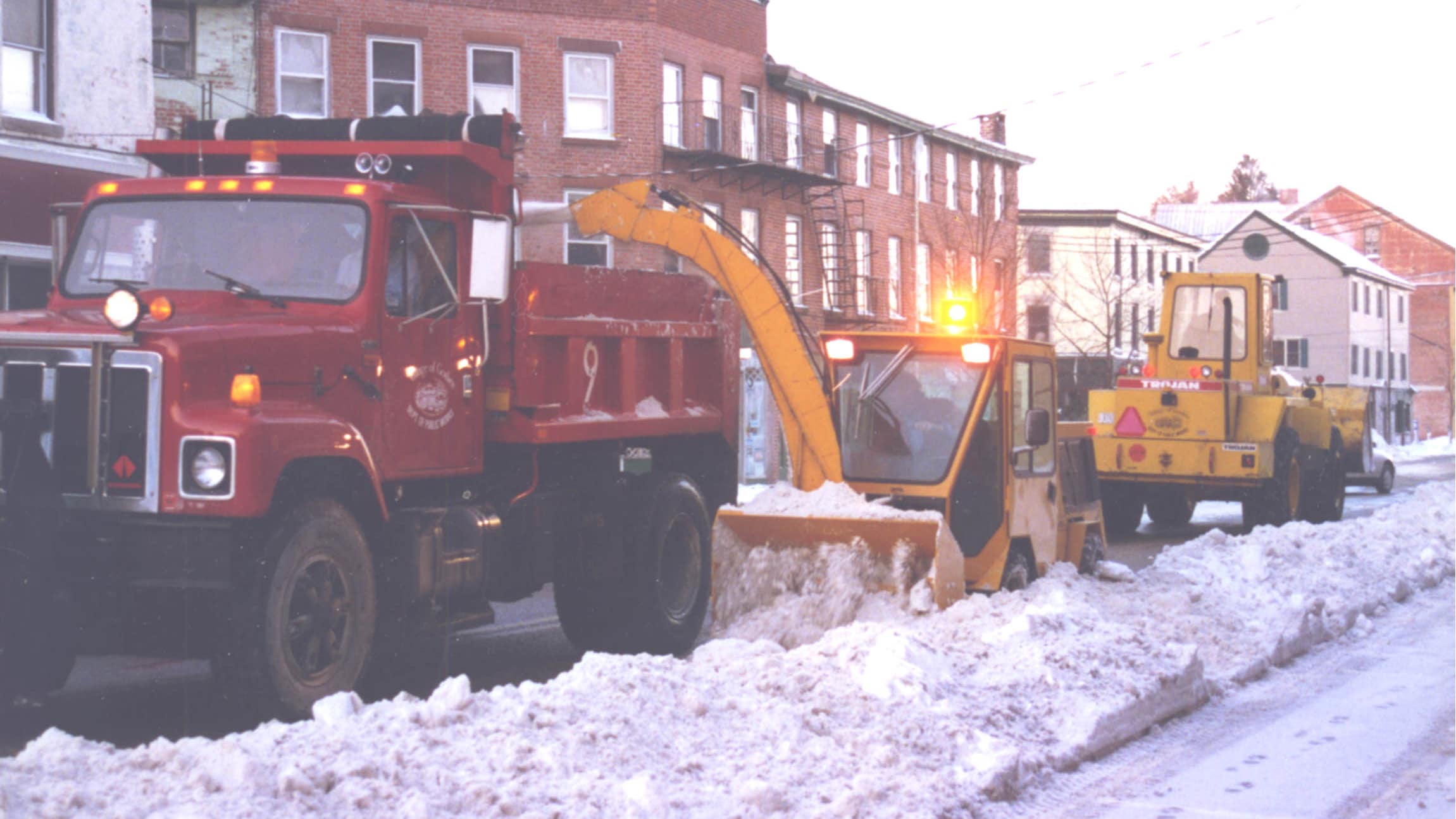 trackless vehicles mt5 tractor machine blowing snow into a large truck with the twin auger snowblower attachment