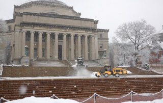 Trackless vehicles tractor with power angle sweeper attachment sweeping snow from stairs at columbia university