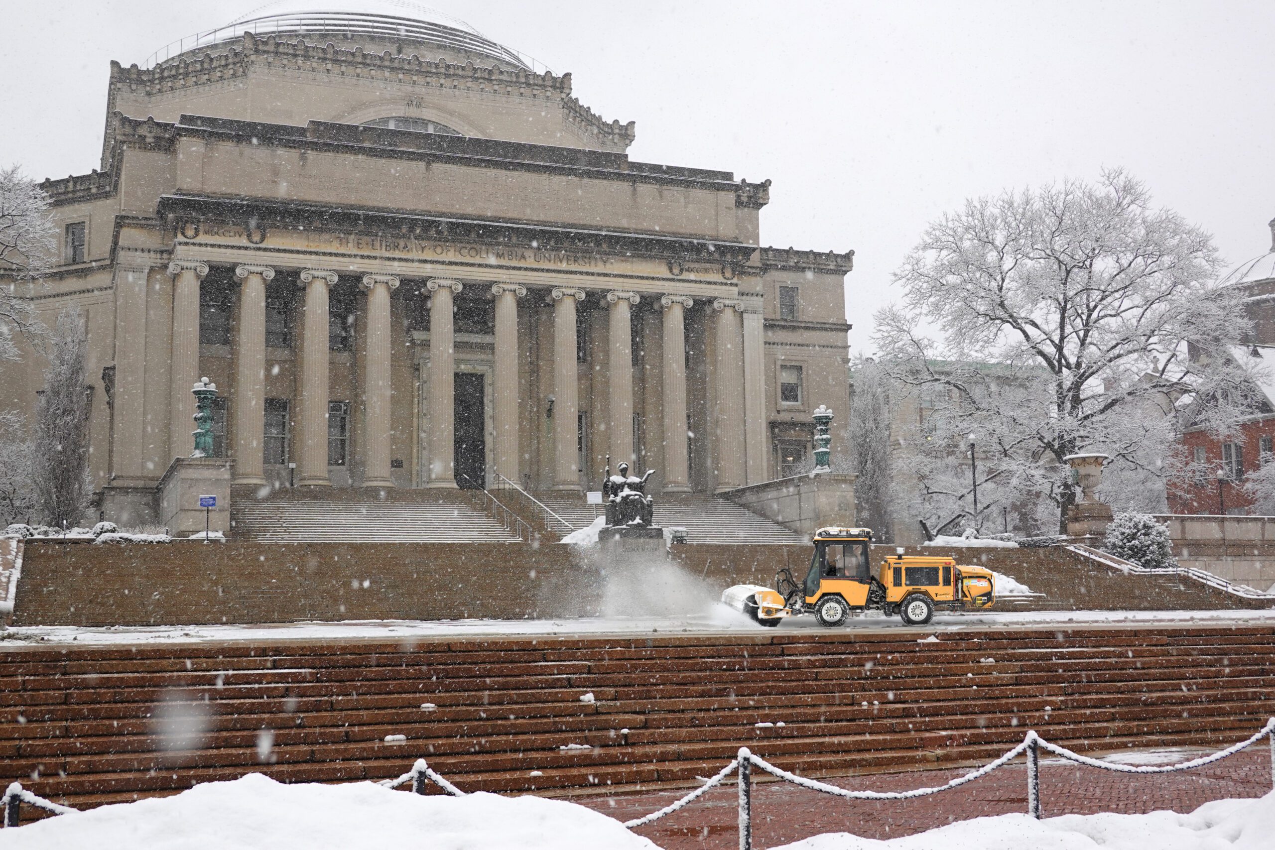 Trackless vehicles tractor with power angle sweeper attachment sweeping snow from stairs at columbia university