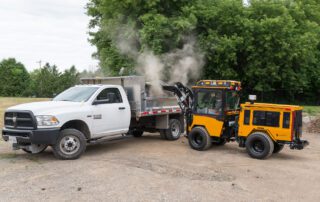 Trackless vehicles tractor with front end loader emptying bucket into truck