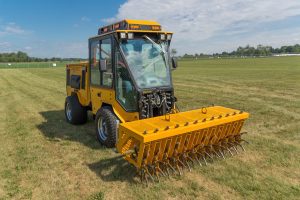 trackless vehicles aerator attachment on sidewalk municipal tractor in field front side view