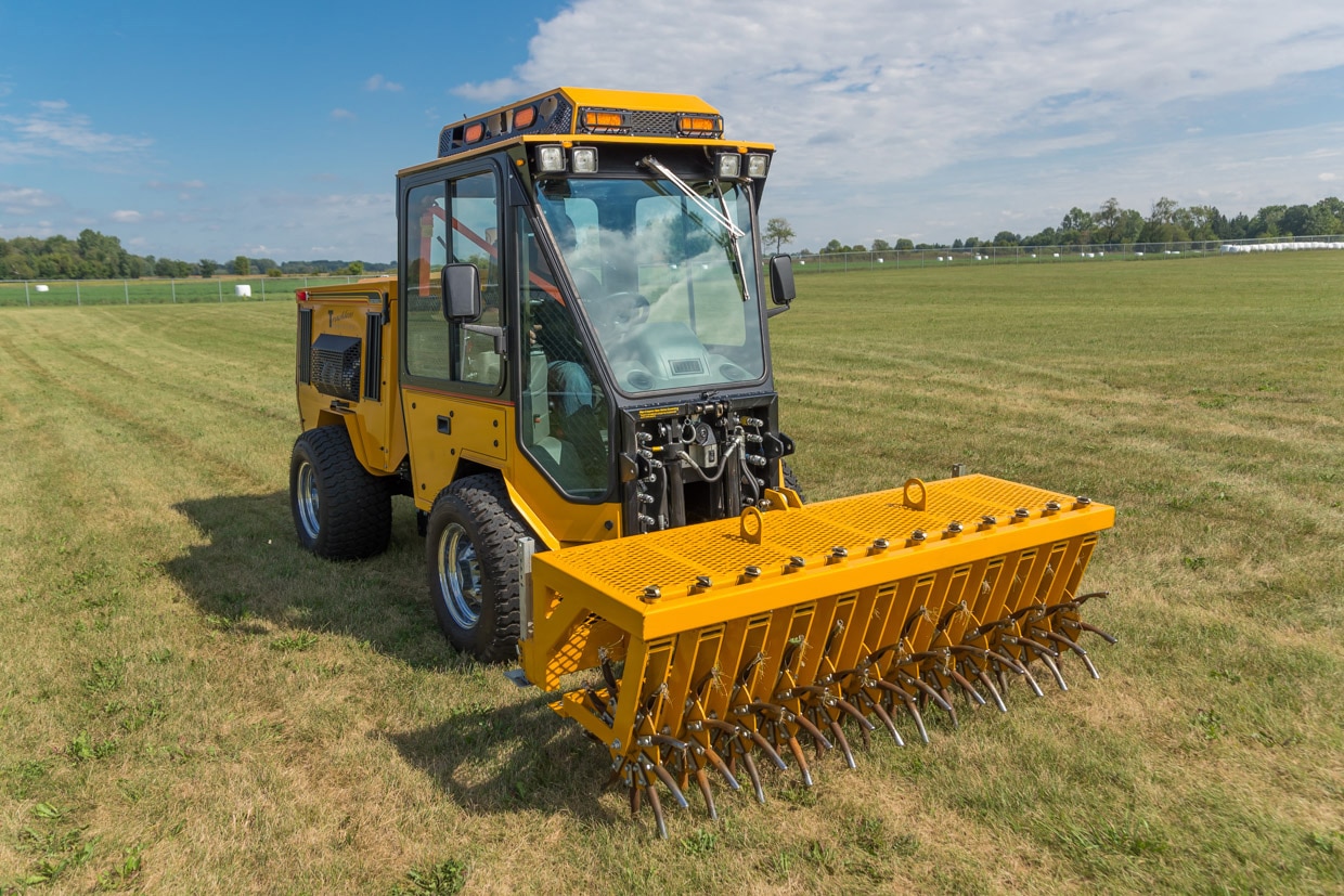 trackless vehicles aerator attachment on sidewalk municipal tractor in field front side view