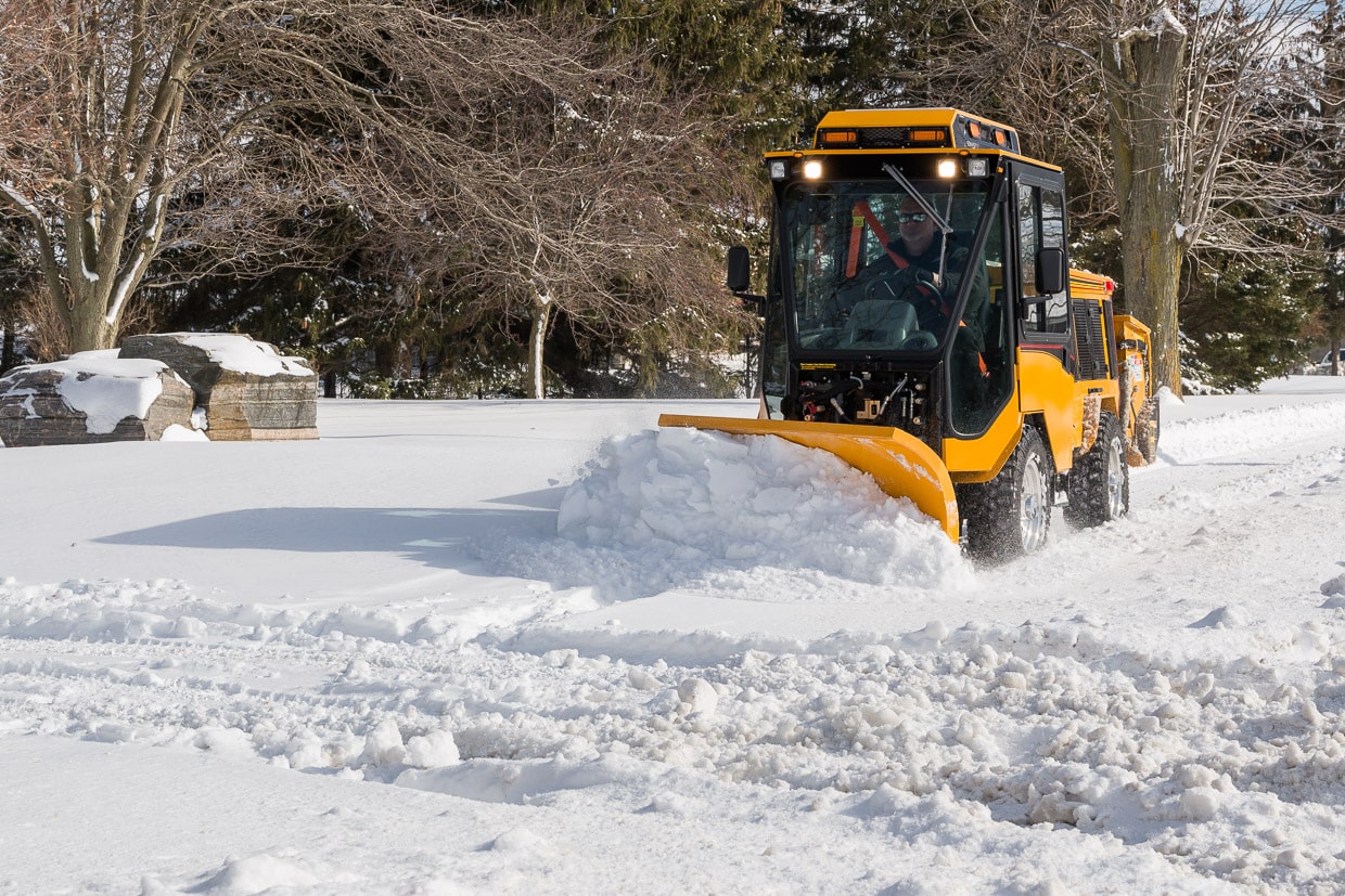 trackless vehicles double trip plow attachment on sidewalk tractor in snow front view