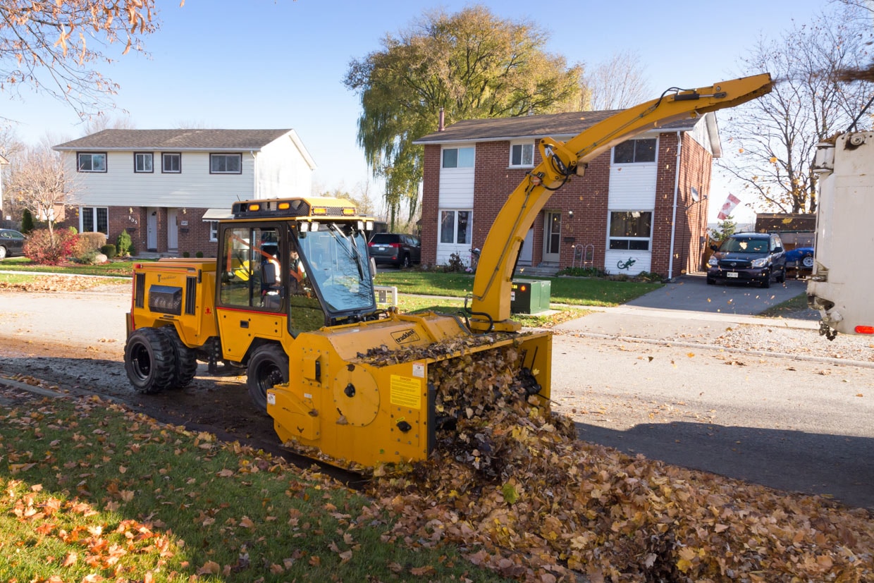 trackless vehicles leaf loader attachment on sidewalk municipal tractor loading leaves side view