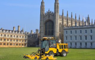 Trackless Vehicles rotary finishing mower mowing the grass in front of big university college campus