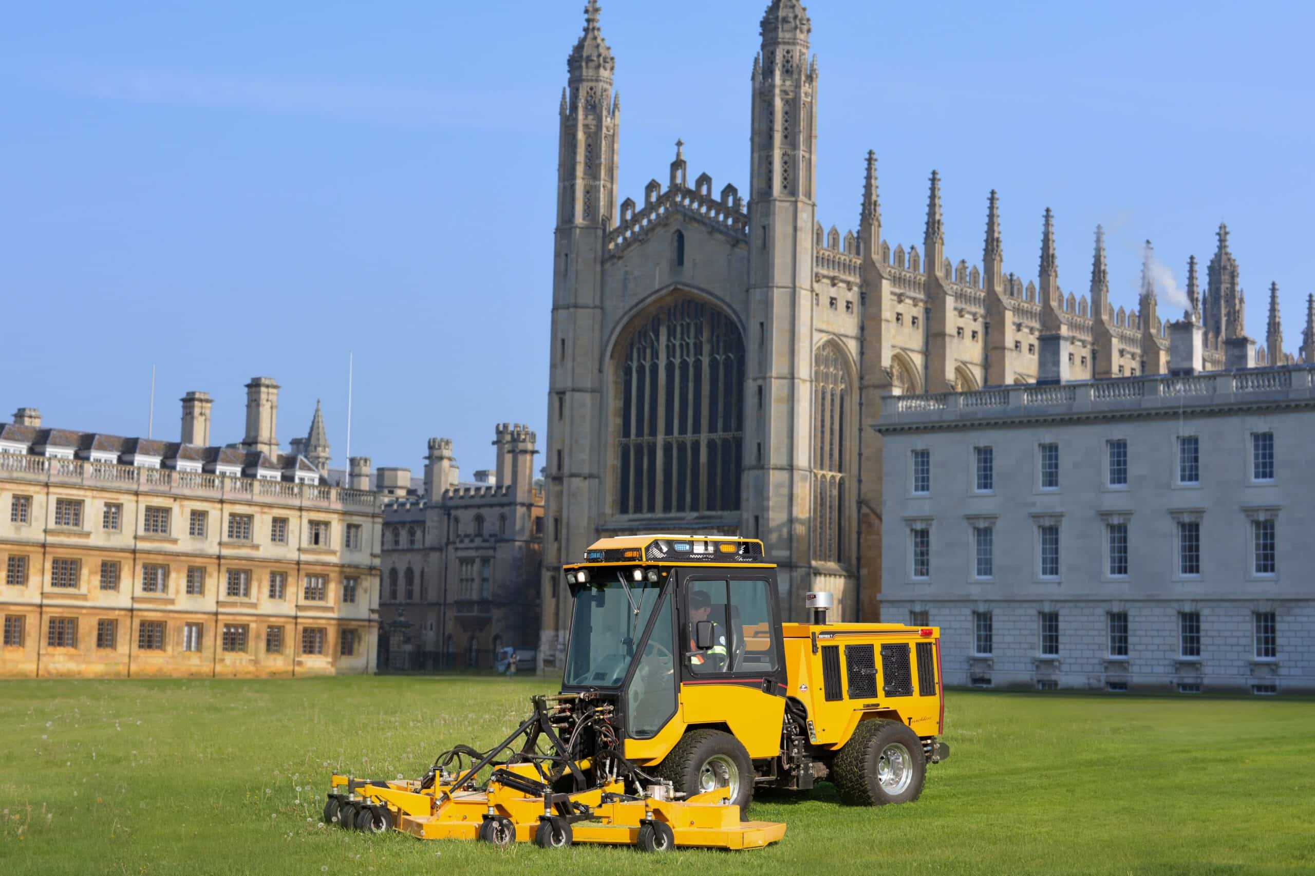 Trackless Vehicles rotary finishing mower mowing the grass in front of big university college campus