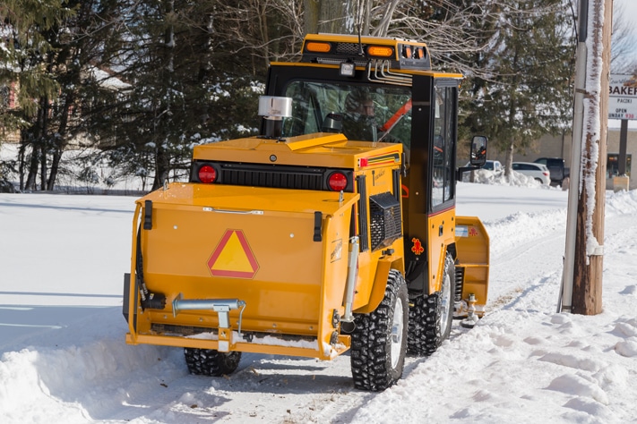 trackless vehicles rear-mount sidewalk spreader attachment on sidewalk tractor in snow on sidewalk