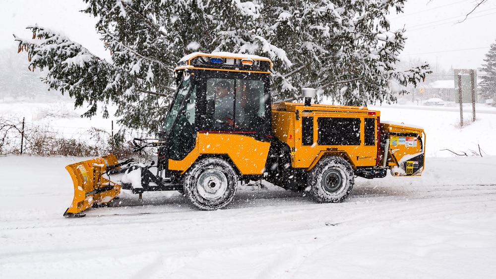 trackless vehicles 5-position folding v-plow attachment on sidewalk tractor in snow side view