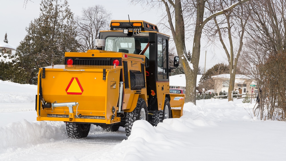 trackless vehicles rear-mount sidewalk spreader attachment on sidewalk tractor in snow