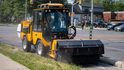 trackless vehicles power angle sweeper attachment on sidewalk municipal tractor sweeping dirt on road